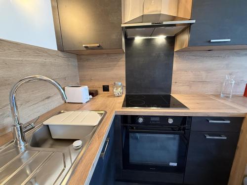 a kitchen with a sink and a stove at Studio Montagne chic centre station in Le Lioran
