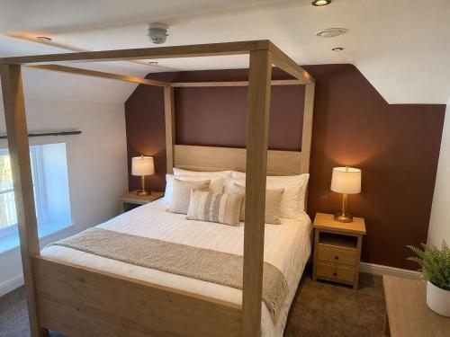 a bedroom with a wooden canopy bed with two lamps at The Hurt Arms in Whatstandwell