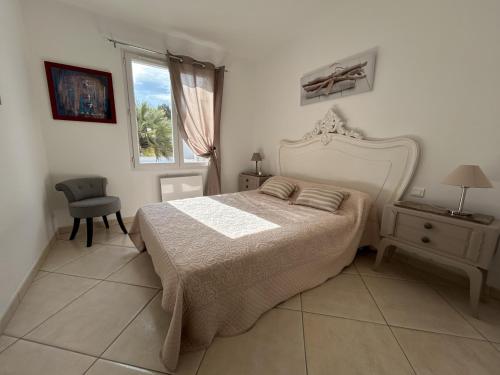 a bedroom with a bed and a chair and a window at Villa du Bonheur Carambole in Saint-Georges-dʼOléron