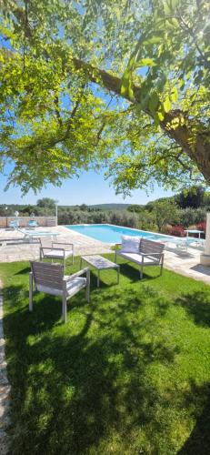 three park benches sitting in the grass near a pool at Casa Relax Isabelle in Alberobello