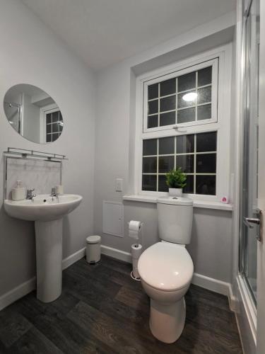 a bathroom with a toilet and a sink and a window at Central Guest House in Newport