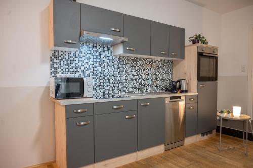 a kitchen with gray cabinets and a tile wall at Paky Appartements 00322 in Bruck an der Leitha