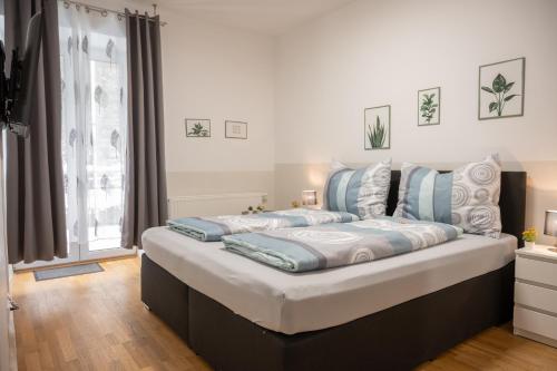 a large bed with blue and white pillows on it at Paky Appartements 00322 in Bruck an der Leitha