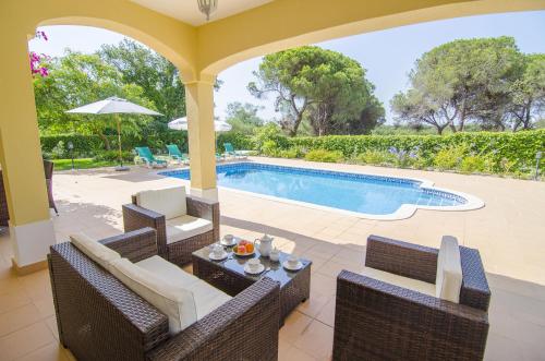 a patio with chairs and a swimming pool at Bonita by Algarve Holidays in Quarteira