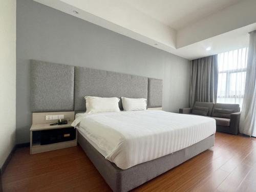 a bedroom with a large bed and a chair at Livingston Hotel in Sandakan