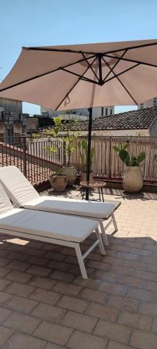 an umbrella and two chairs and a table and a bench at Casa di charme "Al Moro Avola " in Avola