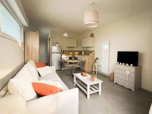 a living room with a white couch and a kitchen at Studio La Parenthèse Sablaise - 3 étoiles in Les Sables-d'Olonne