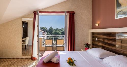 a bedroom with a bed with a view of a balcony at Hotel Terra Nova in Novalja