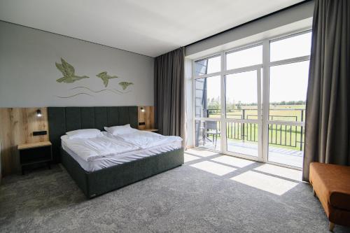 a bedroom with a bed and a large window at Kryla by Shepilska in Dolgoluka
