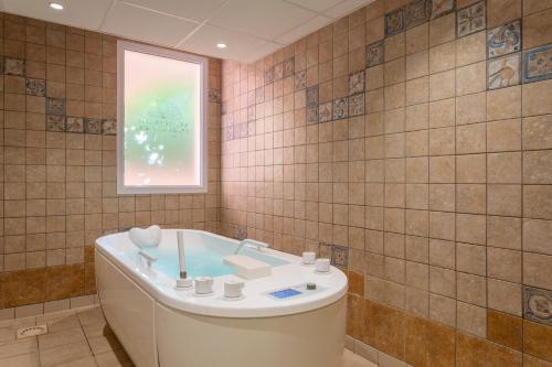 a bathroom with a bath tub and a window at Résidence Pierre & Vacances Premium Les Calanques des Issambres in Les Issambres