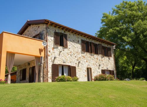 an old stone building with brown shutters on a green field at Scappo in Umbria, Casale Rusinè in Narni