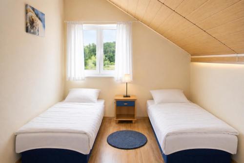 two beds in a small room with a window at DOMKI NA FALI by Baltic Club in Sarbinowo