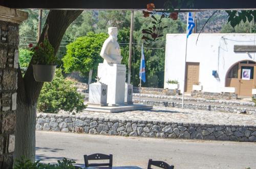 a statue in the middle of a park with two chairs at Platanos Rooms in Anopoli Sfakion