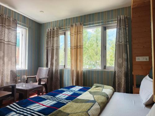 a bedroom with a bed and a table and windows at Hotel Pahalgam Villas in Pahalgām