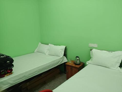 two twin beds in a room with a night stand at Cloud Hill Homestay in Jālāpahār