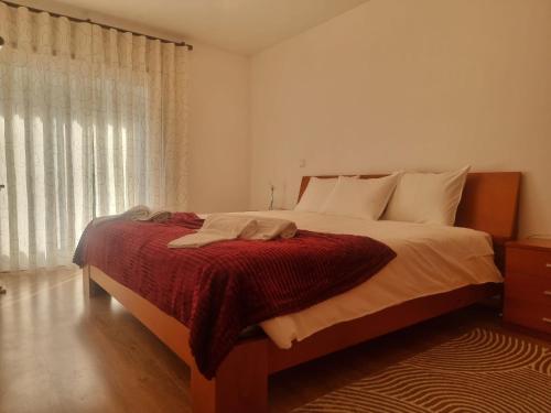 a bedroom with a bed with a red blanket and a window at Minho House in Vieira do Minho