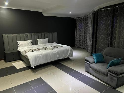 a bedroom with a bed and a couch at Acomodações e Serviços TR in Maputo