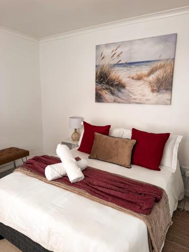 a bedroom with a bed with red and white pillows at Paterson Place Studios in Hermanus