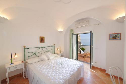 a white bedroom with a bed and a balcony at Casa Alessia in Praiano