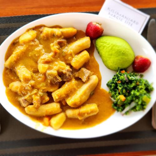 a white plate of food with pasta and a pickle at Kilimanjaro Magic in Moshi