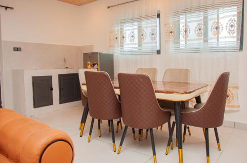 a dining room with a wooden table and chairs at Résidence Maranatha in Cotonou
