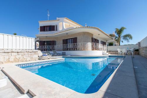 a house with a swimming pool in front of a house at Villa Brisa do Mar by Algarve Holidays in Galé
