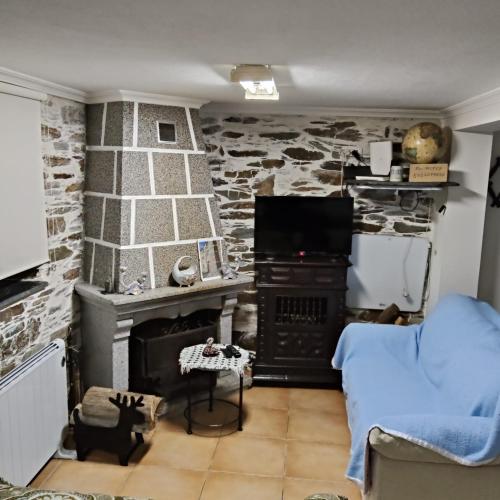 a living room with a stone wall with a stove at Cantinho Casal do Rei in Seia