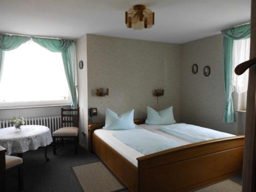 1 dormitorio con cama, mesa y ventana en Hotel Garni am Heuberg en Eschwege