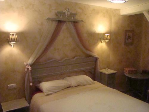 a bedroom with a bed with a canopy and two lights at Le jardin de Saint Jean in Saint-Jean-aux-Bois
