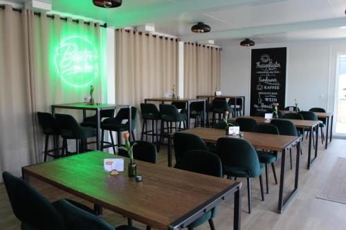 a restaurant with tables and chairs and a green sign at Baumgartner Camping am Inn in Schärding