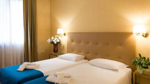 two beds in a hotel room with towels on them at Hotel Lombardia in Milan