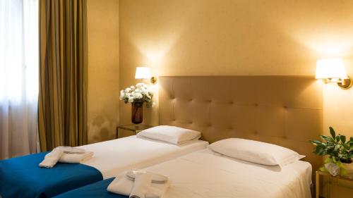 two twin beds in a hotel room with flowers at Hotel Lombardia in Milan