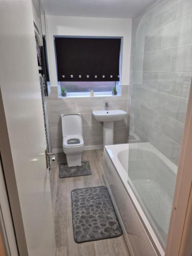 a bathroom with a toilet and a sink and a bath tub at Stylish 2-Bed Flat, Minutes to Southport Centre in Southport