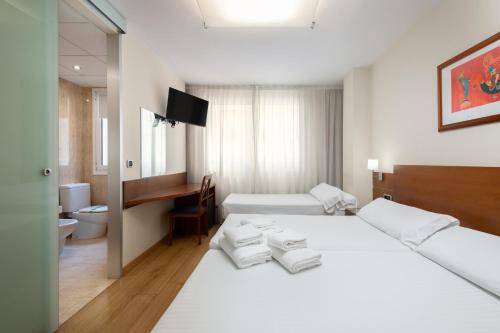 a hotel room with a white bed and a desk at Hotel Longoria Plaza by Pandora Hoteles in Oviedo