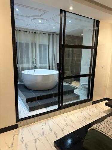 a bath tub in a room with a large glass window at Duplex MNE in Douala