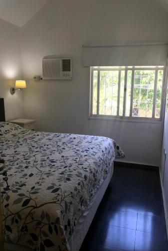 a bedroom with a bed with a floral bedspread and a window at Duplex SM con ESTACIONAMIENTO in San Juan