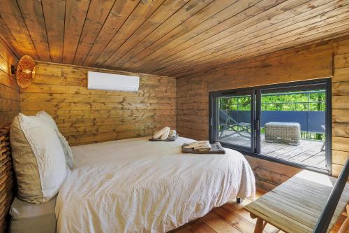 a bedroom with a bed in a wooden room with a window at Cabane Spa - Noyers - Proche Sarlat in Jayac