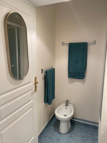 a bathroom with a white toilet and green towels at Dolce Vita à Nice in Nice