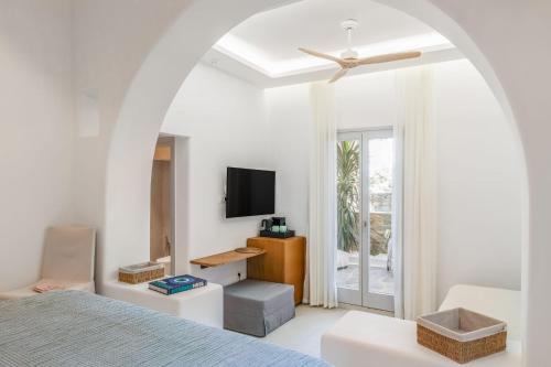 a white bedroom with a bed and a tv at Elena Hotel Mykonos in Mikonos