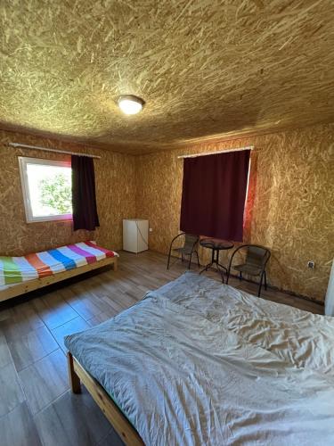 a bedroom with a bed and two chairs and a window at Tóparti Camping in Tiszafüred