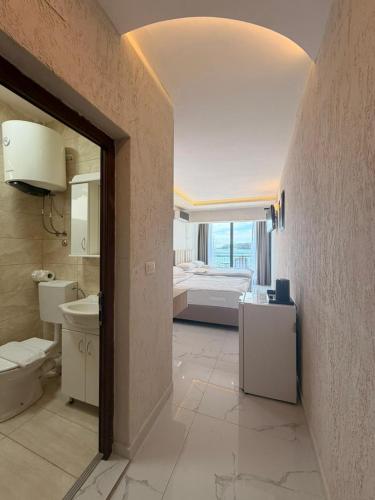 a bathroom with a bedroom with a bed and a sink at Beachfront Hotel Palma - Jaz in Budva
