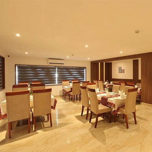 a dining room with tables and chairs in a restaurant at Hotel Salkara Chavakkad in Manattala