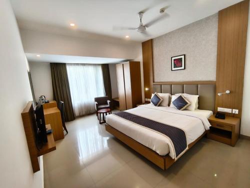 a hotel room with a large bed and a chair at Hotel Salkara Chavakkad in Manattala