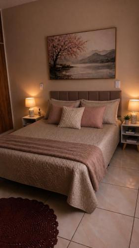 a bedroom with a large bed with two tables and two lamps at Recanto Sossego Wi-Fi 3 quartos 3 banheiros 2 chuveiros Espaço amplo churrasqueira in Espirito Santo Do Pinhal