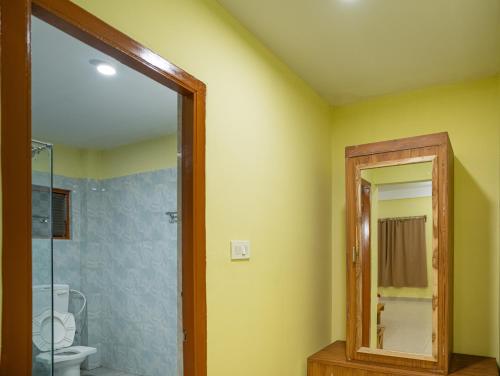 a bathroom with a shower and a toilet and a mirror at Resort Bihanga in Chālsa Mahābāri