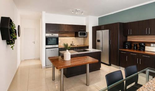 a kitchen with wooden cabinets and a wooden table at Sunset Sails 2 Apartment in Langstrand