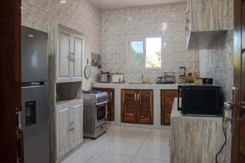 a kitchen with white cabinets and a tv in it at L'appartement Bleu d'Assinie in Assinie