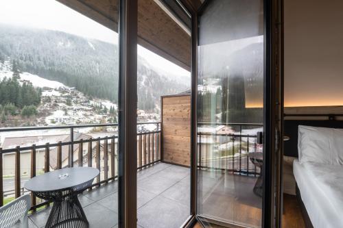 a room with a balcony with a bed and a table at Hotel Krone - Aktiv & Erholt in Churwalden