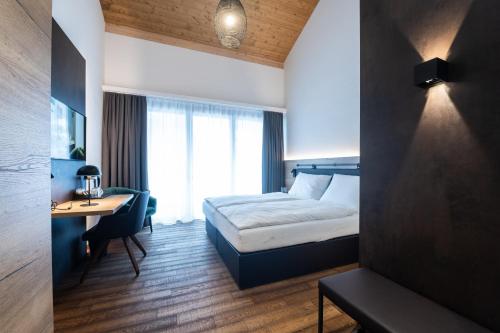 a hotel room with a bed and a desk and a bed and a window at Hotel Krone - Aktiv & Erholt in Churwalden