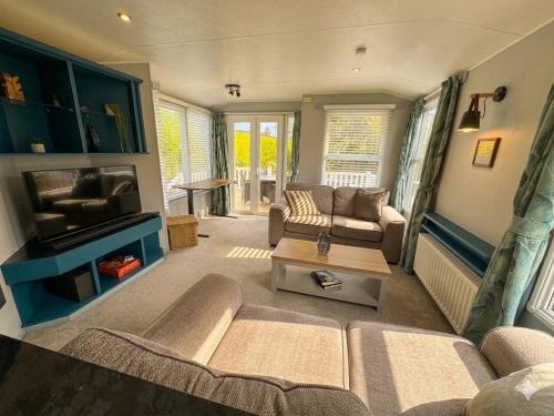 a living room with a couch and a tv at Bag End, Near Porth Beach, Garden & Stream in Newquay Bay Resort
